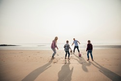 Wide angle view of a family playing football at the beach.