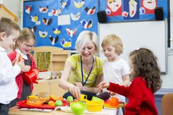 Nursery teacher playing kitchen role play with her students in the classroom. 
