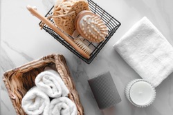 On a marble background a set of various bath accessories. Terry towel, soap, comb, oil, shampoo, loofah washcloth and candles. The view from the top