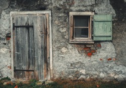 Old vintage barn wall with wooden window and worn wooden door.
