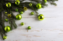 Christmas background decorated with green ornaments. New year greeting card with bauble hanging. Copy space.
