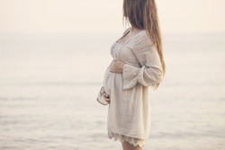beautiful pregnant woman standing on the beach