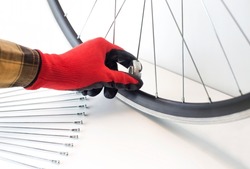 part of a bicycle wheel, adjusting the spokes of the wheel with a tool, close-up, on an isolated white background