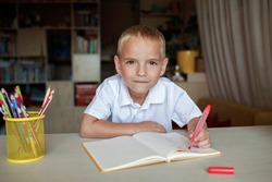 Happy left-handed boy writing in the paper book with his left hand, international left-hander day celebration, only lefties understand