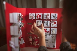 Pretty girl opens an original advent calendar like a book made of jewelry boxes and a binder, New Year craft, diy. Magic of moment, seasonal activity. Christmas miracle. Soft focus, depth of field