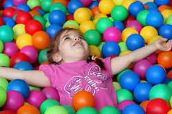 Happy girl playing and having fun at kindergarten with colorful balls, family weekend concept, happy birthday and merry party