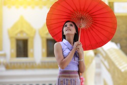 Cute Burmese women with traditional  Burma dress holding red umbrella walk in temple 