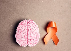 World Multiple Sclerosis Day. Orange awareness ribbon and brain symbol on a brown background.