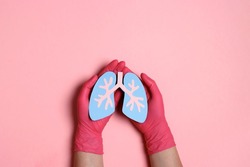 Hands with medical gloves hold a lungs symbol on pink background. World Tuberculosis Day. Healthcare, medicine, hospital, diagnostic, internal donor organ.