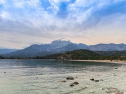 Cloudy sunset sky on the Mediterranean Sea and mountains from Phaselis Ancient City Coast, Antalya, Türkiye.