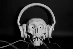Hearing damage - skull wearing protective ear headphones isolated on black background. Skull with headphones 