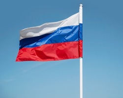 Russian tricolor flag waving in the wind against  sky. Russian flag on blue sky background