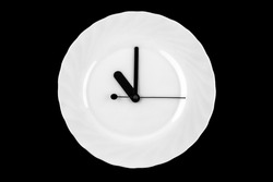 Lunch time clock. plate with clock. clock hands on white dish.  black background. eleven o'clock