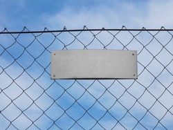 blank sign on a dangerous zone. Closed area, fenced with metallic mesh and yellow warning plate. Blank billboard on the wall. white empty blank sign with copy space attached to metal fence outdoors.
