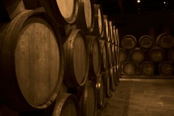 Wooden barrels of aged wine. Old wine cellar with many oak barrels, equipment for wine production. barrels in cellar. Rows of wine and cognac barrels in the basement of winery. Process of aging.