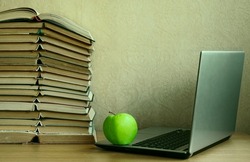 Modern formation and online learning. Laptop computer, fresh green apple and stack of books. wallpaper background. schooling at home idea. Back to school concept. wooden desktop. online education