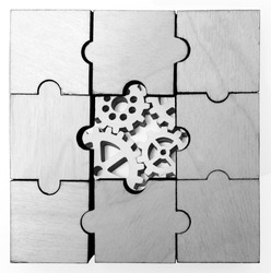  wooden gears under the puzzle, the concept of moving to the next level. Cog wheels coming out from underneath a jigsaw puzzle. solving the problem concept - puzzles and cogwheels.
