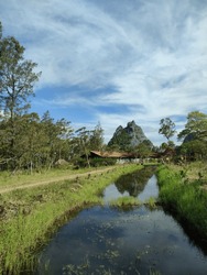 stream beside country road with rocky mountains and blue sky in the background