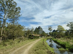 stream beside country road with rocky mountains and blue sky in the background