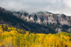 Cloudy rock ridge seen from Ohio Creek Road with the colorful of fall foliage autumn season of Aspen groves, Gunnison, Colorado, USA