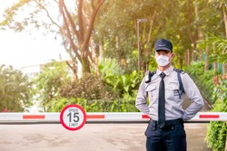 Asian security guard make saluting entry entrance the village. Security Guard with mask, protect covid-19 warning. Guard check entrance to the village. Speed 15 limit in area, copy space.