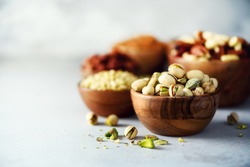 Pistachios nuts in wooden bowl. Food mix background, top view, copy space, banner. Assortment of nuts - cashew, hazelnuts, almonds, walnuts, pistachio, pecans, pine nuts, peanut, raisins.
