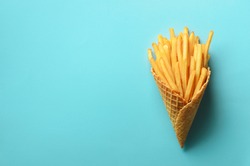 Fried potatoes in waffle cones on blue background. Hot salty french fries with tomato sauce, basil leaves. Fast food, junk food, diet concept. Top view. Minimal style. Pop art design, creative concept