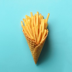 Fried potatoes in waffle cones on blue background. Hot salty french fries with tomato sauce. Fast food, junk food, diet concept. Top view. Minimal style. Pop art design, creative concept
