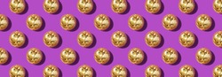 Creative Christmas pattern. Shiny gold disco balls over violet background. Flat lay, top view. New year baubles, star sparkles. Party time. Cristmas greeting card.