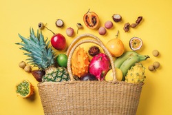 Exotic fruits in straw summer bag. Tropical pineapple, banana, pitahaya, kiwano, african horned melon, tamarillo fruit, granadilla, salak, snake fruit, maracuya, rambutan, lychee, longan, tamarind