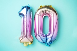 Rainbow foil balloon number, digit ten. Birthday greeting card with inscription 10. Anniversary concept. Top view. Colored numeral on blue background. Numerical digit, Celebration event, template.