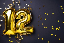 Gold foil balloon number, digit twelve. Birthday greeting card, inscription 12. Anniversary celebration event. Banner. Stylish golden numeral, light bokeh, glitter, black background. Numerical digit.