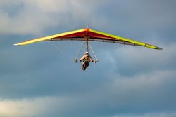 Beginner girl pilot withcolorful hang glider wing. Learning hang gliding. Extreme sports activity