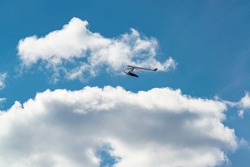 Flying wing in the sky with clouds. Hang glider or rigid wing silhouette