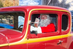 Santa driving in his vintage red hot rod car