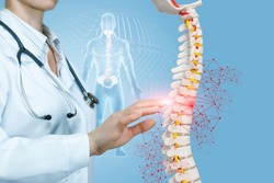 A closeup of doctor operating with artificial spine model with pelvis unit of human skeleton digital human figure background. The concept of spine diseases treatment.