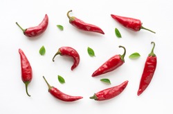 Red hot chilli peppers with green leaves on white background. Food pattern. 