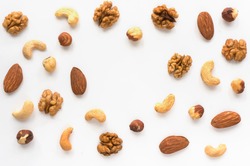 Isolated nuts pattern backdrop with copy space. Walnut, cashew, almond and hazelnut  on white background. Top view. 