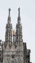 Artistic and picturesque photo of a detail of the Milan Cathedral (Metropolitan Cathedral of the Nativity of the Blessed Virgin Mary) symbol of the Lombard capital surrounded by a sky full of clouds.
