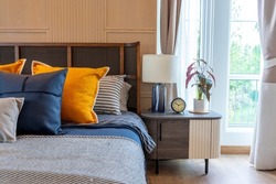 cozy furnished bedroom an accent of blue and yellow pillow. Room furniture with table lamp and carpet.