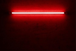 red neon light bulb on cement wall.