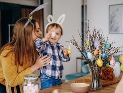 Mother and child draw on Easter eggs and hang them on branches. Preparation of decorations for Easter in the home interior