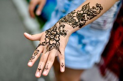 Picture of human hand being decorated with henna tattoo