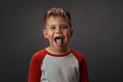 Little cute child. shows his tounge. is isolated on grey background. High quality photo