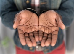 Close up open hands of a young african american man wearing denim jacket. Begging hands of a poor man concept. Young african american man with outstretched hands begging for money for life.