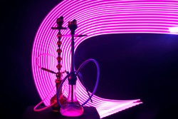 two hookahs with shisha coals pink neon lighting on a dark background