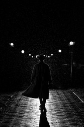 dark silhouette of a man in a coat and hat in the rain on a night street in the city in the style of Noir