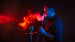 man is smoking a hookah in a bar and blowing a cloud of smoke