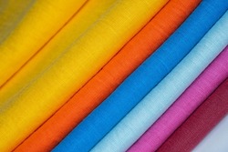 A stack of multi-colored bright linen fabric, close-up. Linen background. Fabric stripes