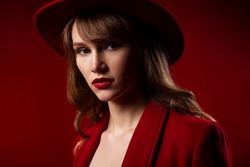 Fashion, beauty portrait of young elegant woman wearing total red luxury outfit, with red lips makeup, posing in studio. Copy, empty space for text
